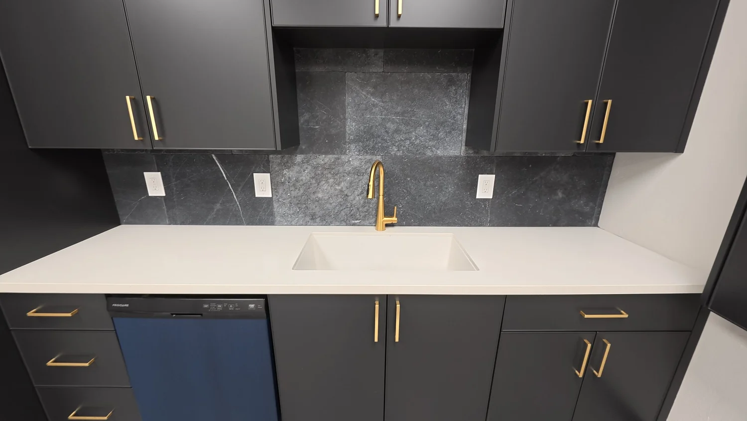 Modern law office kitchenette with navy cabinets, quartz counter and brass fixtures