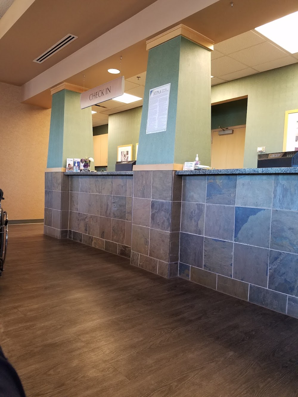 Medical check-in reception counter with slate tile and green columns at AZ Spine & Joint Hospital