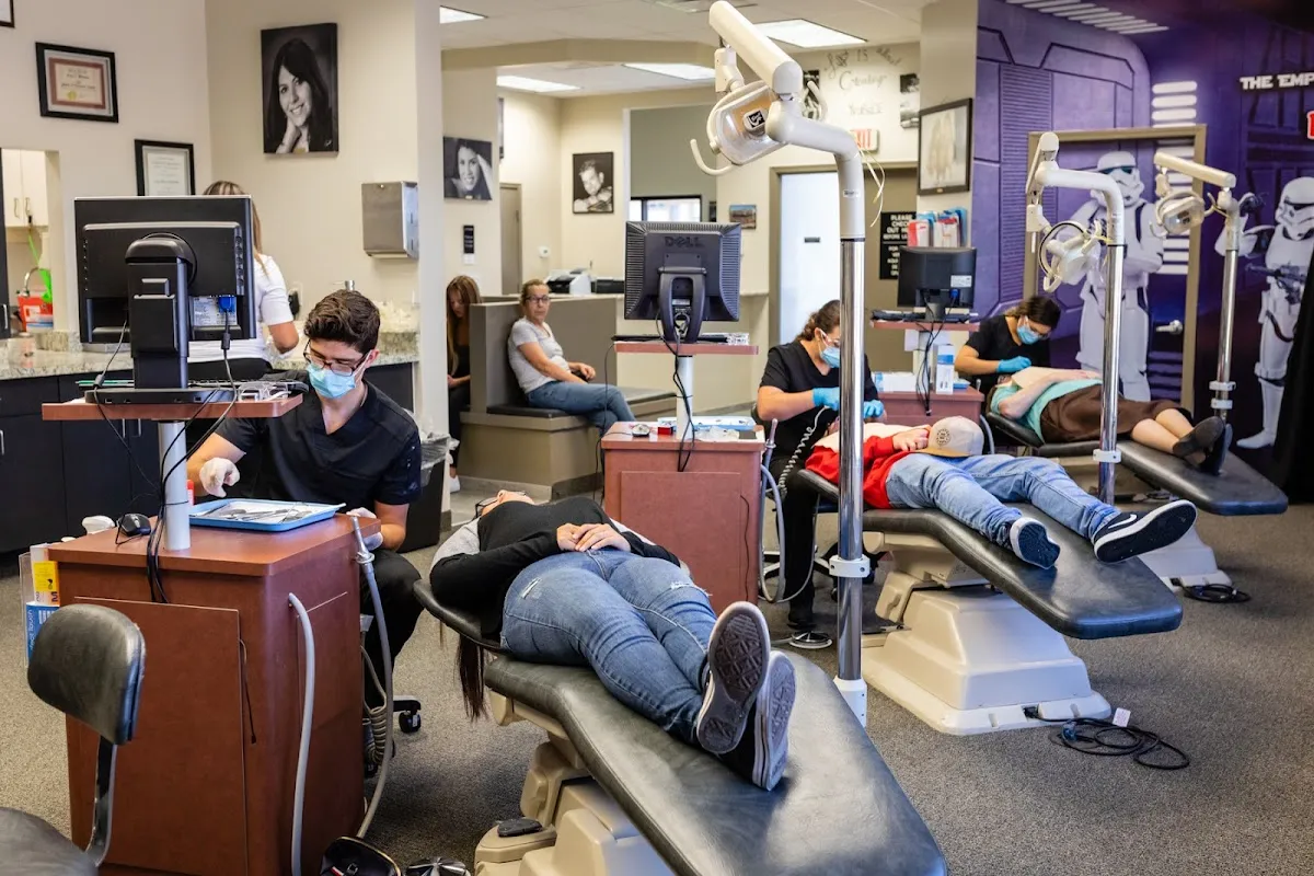 Orthodontic clinic treatment bay with patients in dental chairs and clinical staff